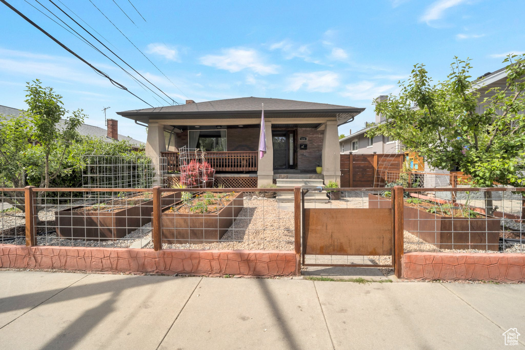 View of front of property with a vegetable garden, a porch, a fenced front yard, and a gate