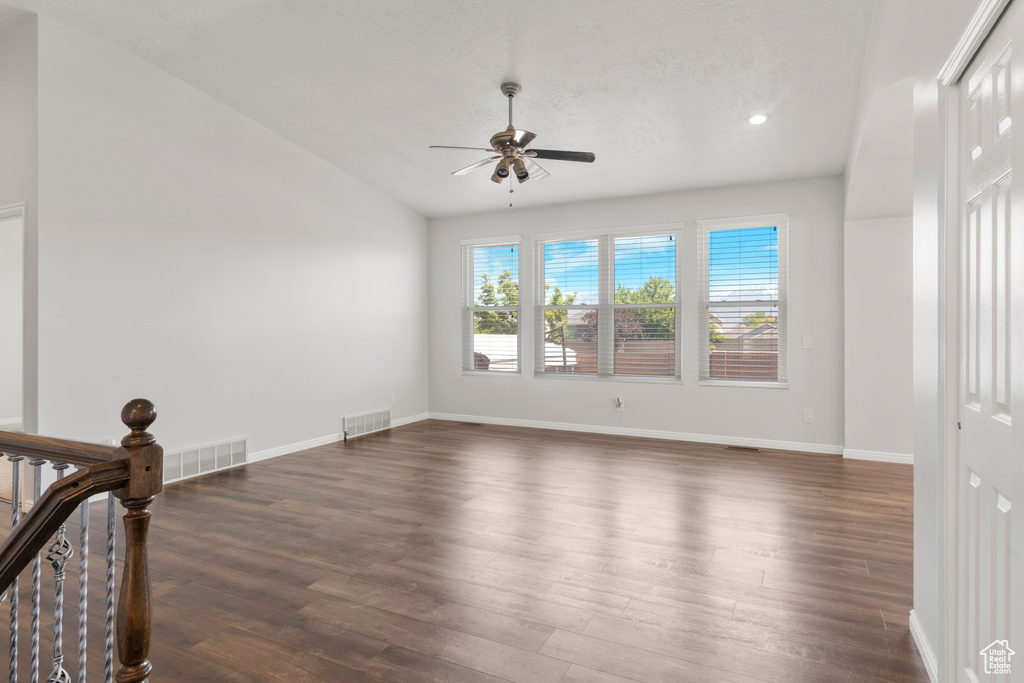 Empty room featuring ceiling fan, dark wood finished floors, baseboards, recessed lighting, and vaulted ceiling