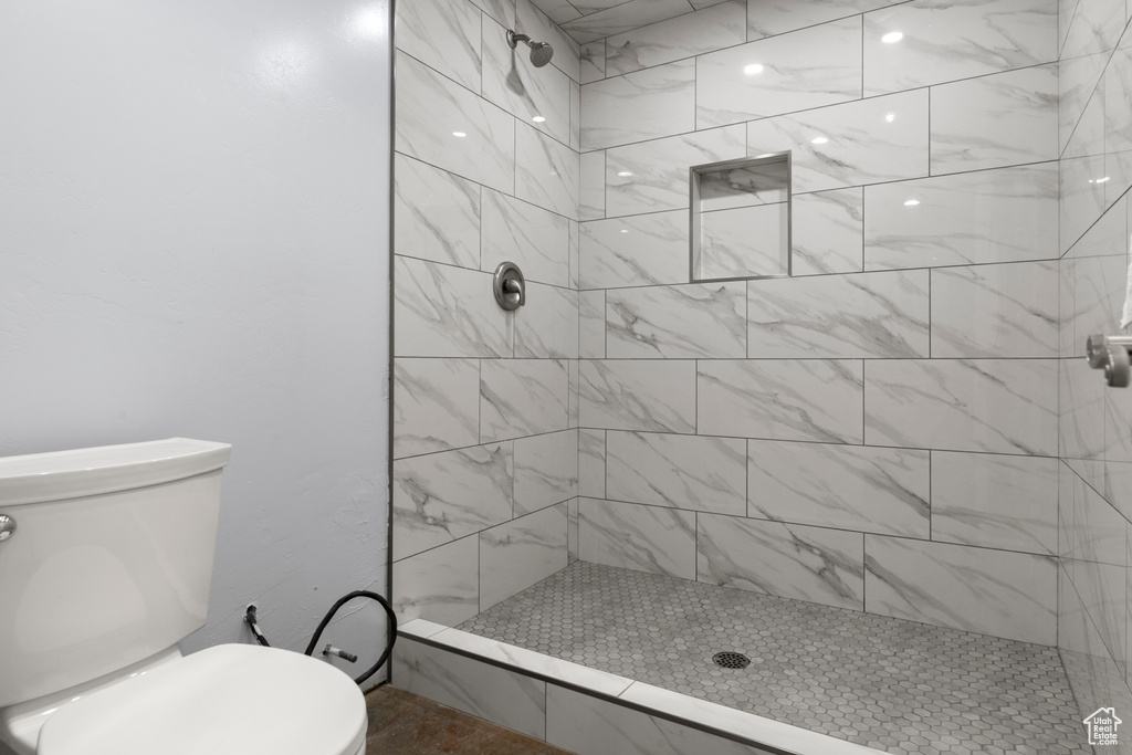 Bathroom featuring tiled shower and toilet