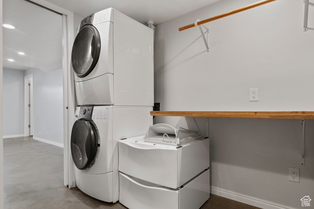 Washroom with stacked washer / drying machine, baseboards, and recessed lighting