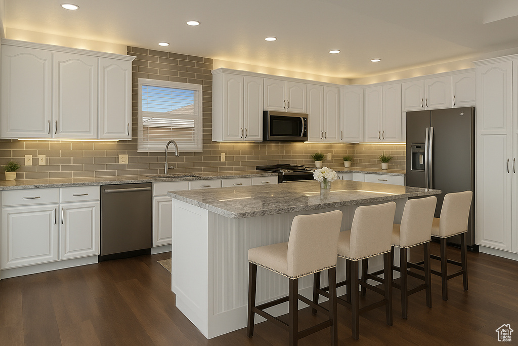 Kitchen featuring appliances with stainless steel finishes, a sink, dark wood-style floors, a breakfast bar, and recessed lighting
