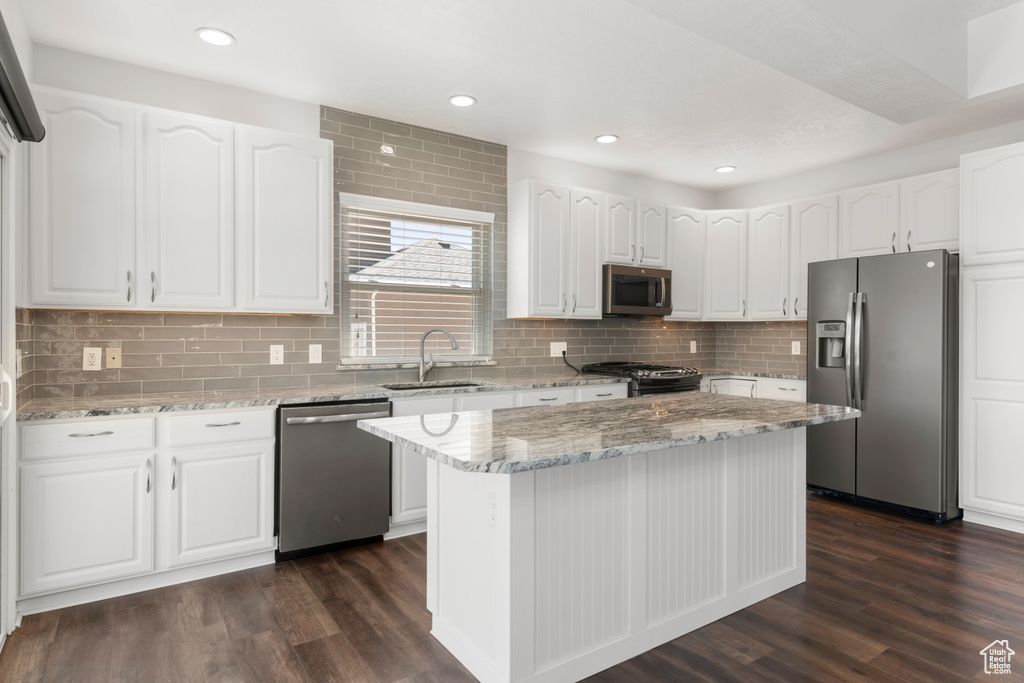 Kitchen featuring appliances with stainless steel finishes, dark wood-type flooring, light stone counters, white cabinetry, and recessed lighting
