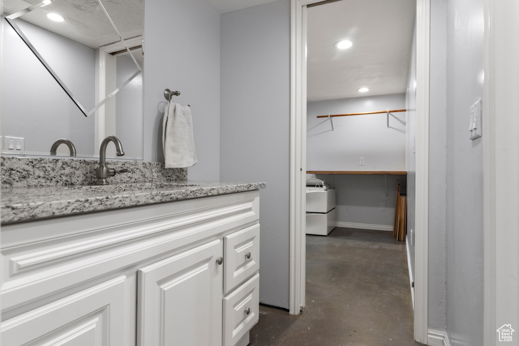 Bathroom featuring finished concrete flooring, vanity, and recessed lighting