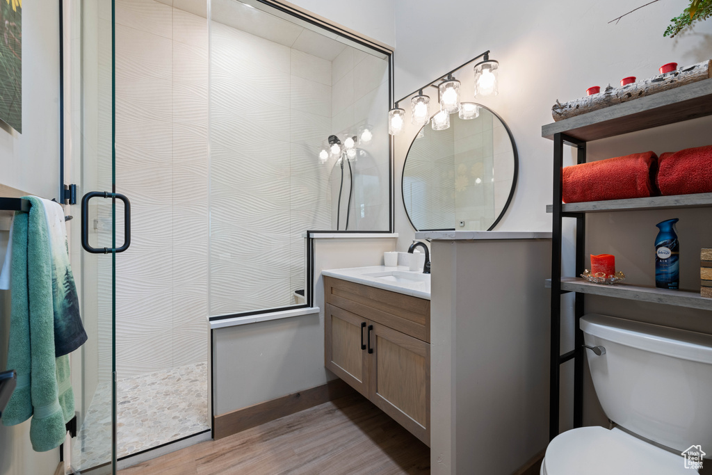 Full bath with vanity, wood finished floors, a shower stall, and toilet