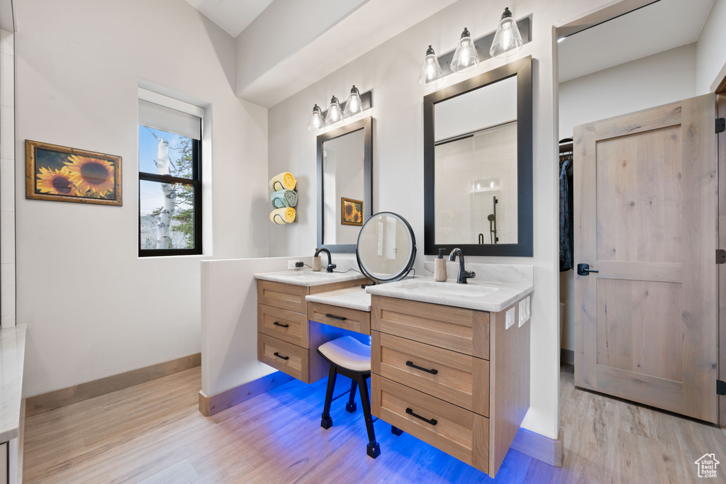 Bathroom featuring wood finished floors, baseboards, and two vanities