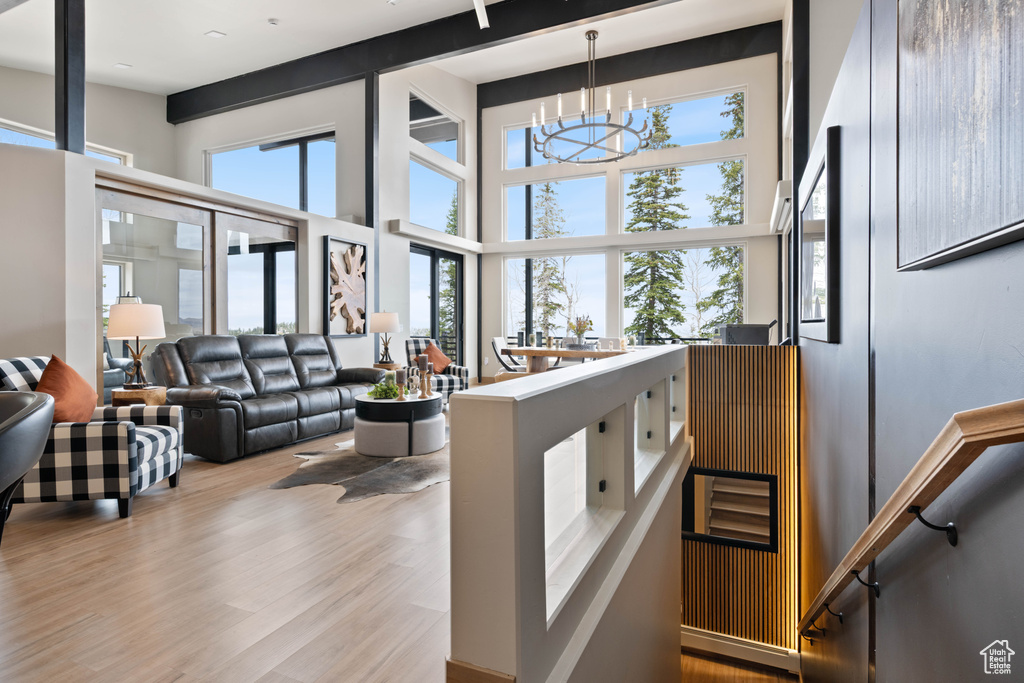 Living area with a chandelier, wood finished floors, and a towering ceiling