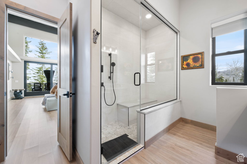 Ensuite bathroom with a shower with door, wood finished floors, and baseboards