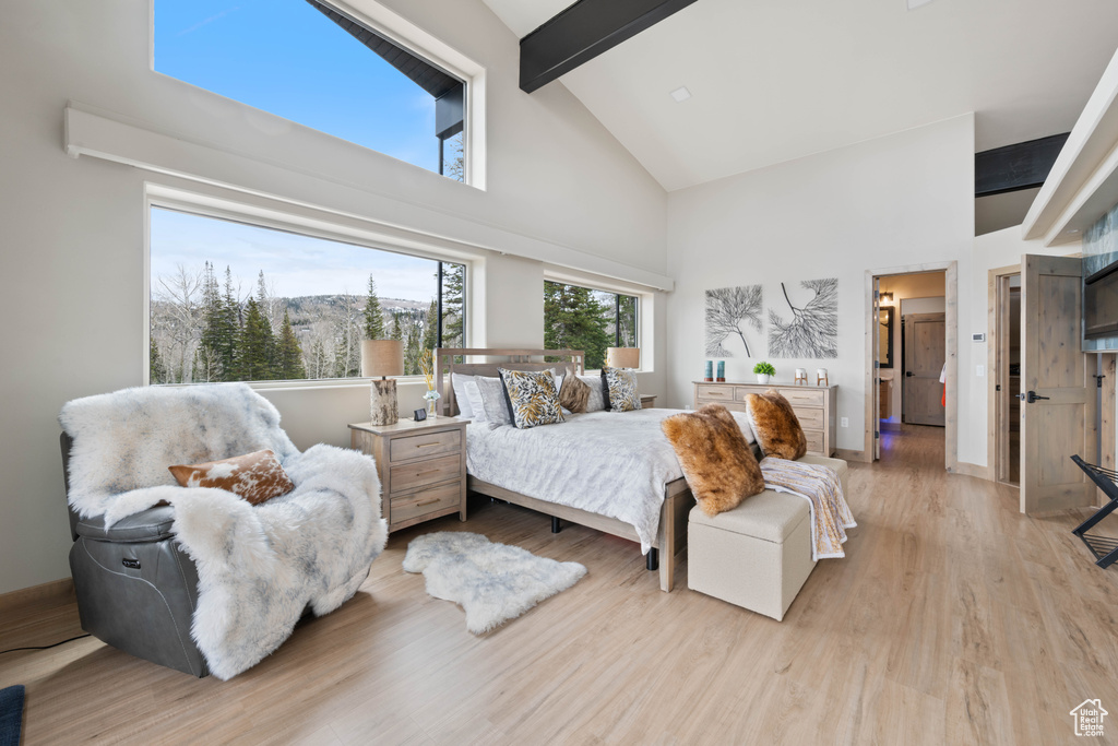 Bedroom featuring high vaulted ceiling, beam ceiling, wood finished floors, and baseboards