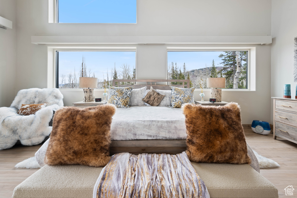 Bedroom featuring a towering ceiling, wood finished floors, and multiple windows