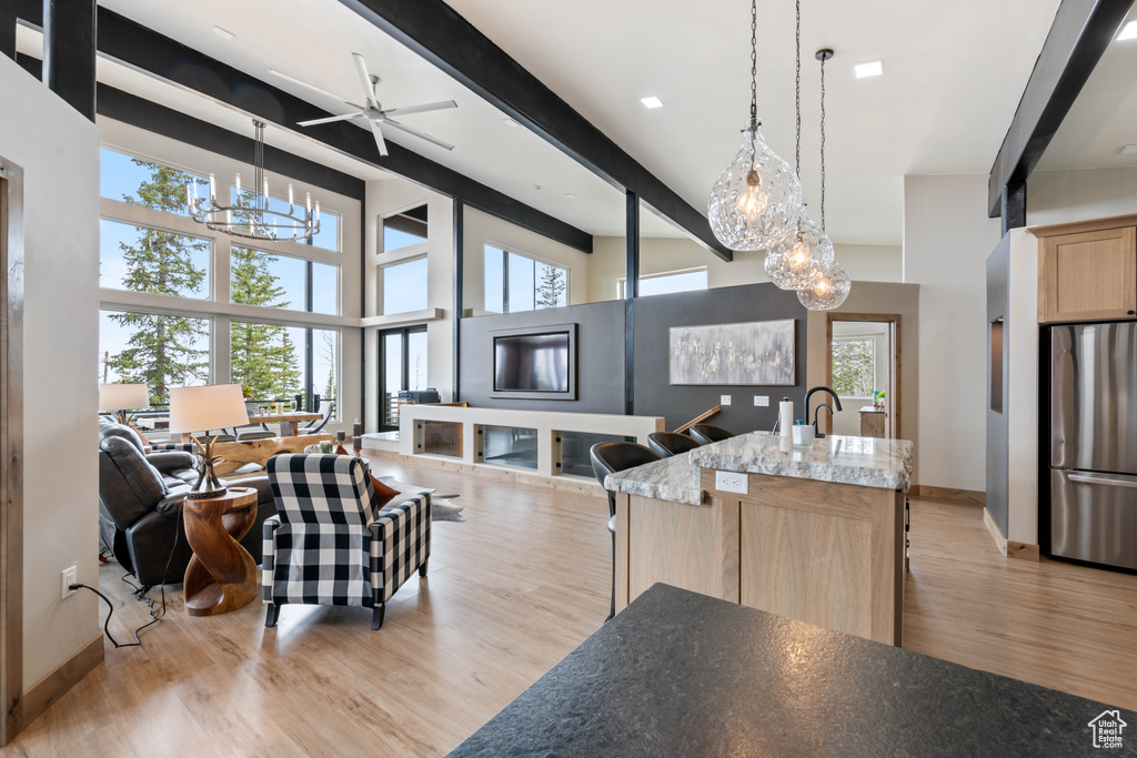 Dining space with a chandelier, light wood finished floors, beamed ceiling, baseboards, and ceiling fan