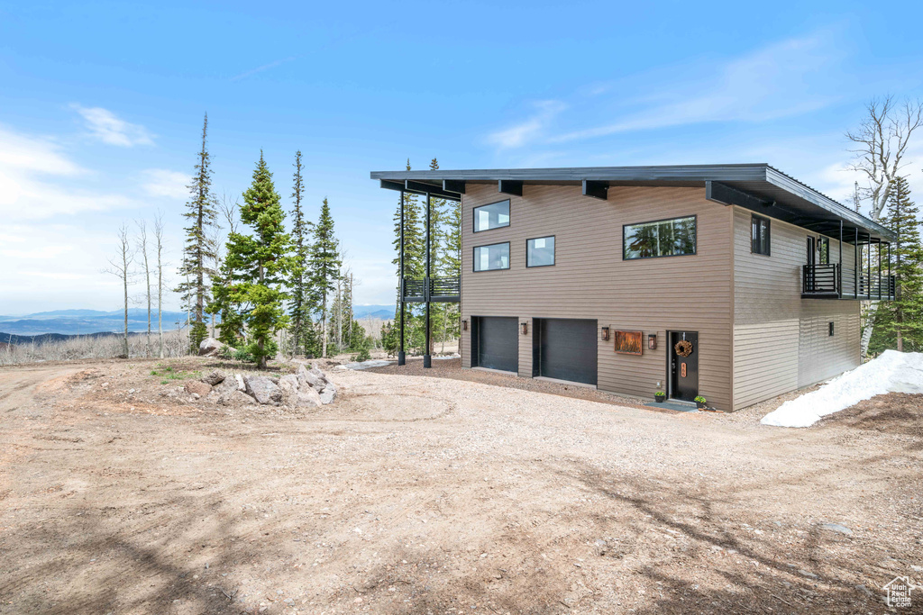 View of side of property featuring a garage, dirt driveway, and a mountain view