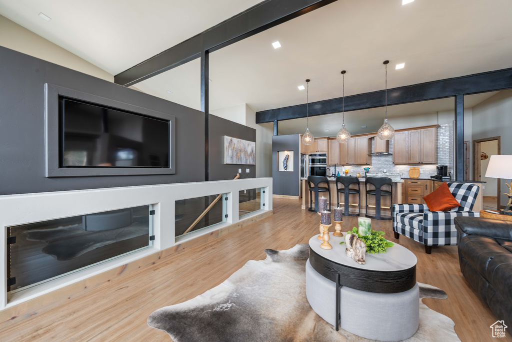 Living room featuring light wood-style floors, beamed ceiling, and high vaulted ceiling