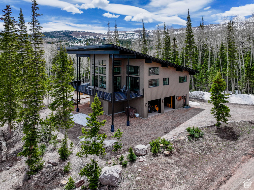 View of front of property featuring driveway, a mountain view, and a sunroom