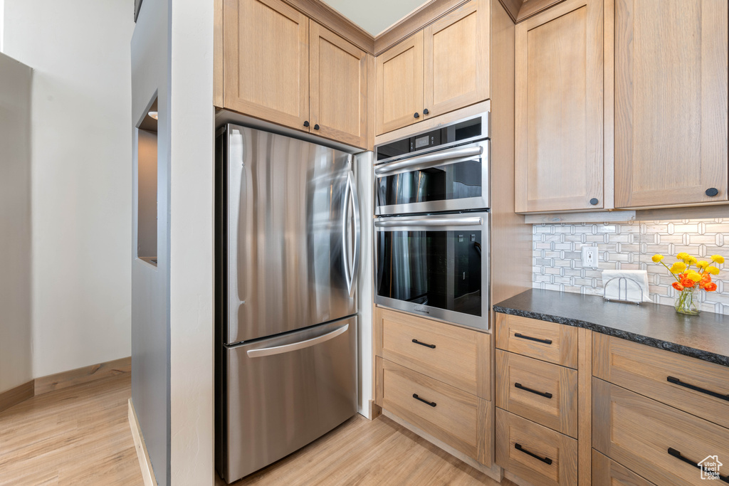 Kitchen with stainless steel appliances, light brown cabinetry, and light wood finished floors