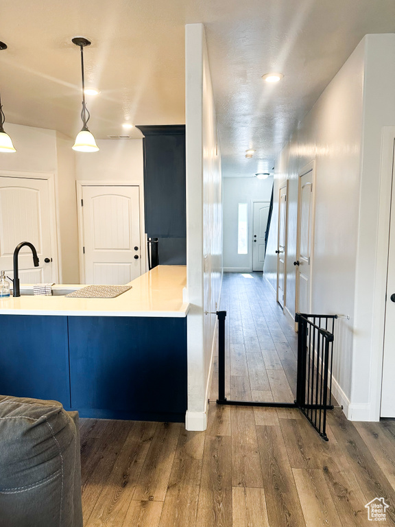 Kitchen featuring hardwood / wood-style floors, decorative light fixtures, light countertops, and a peninsula