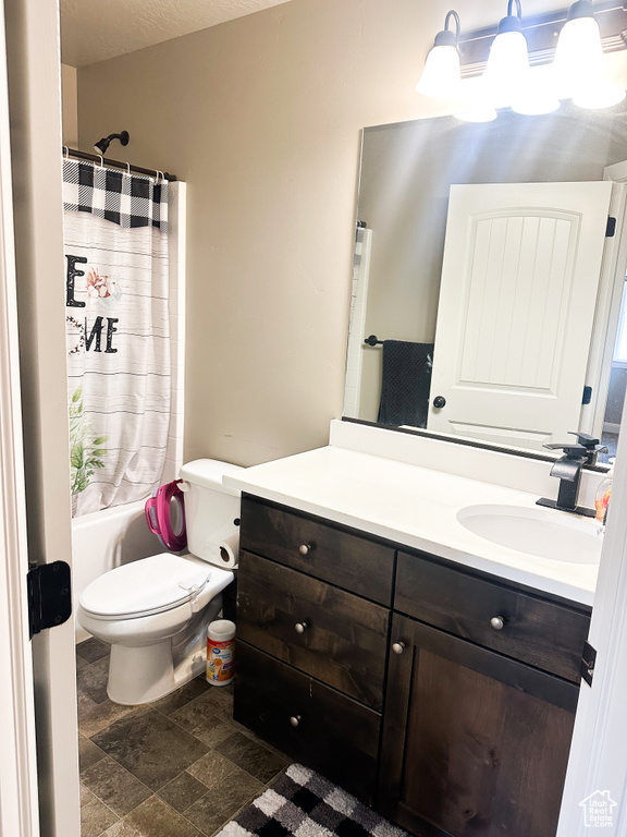 Full bathroom with vanity, stone finish floors, and shower / tub combo