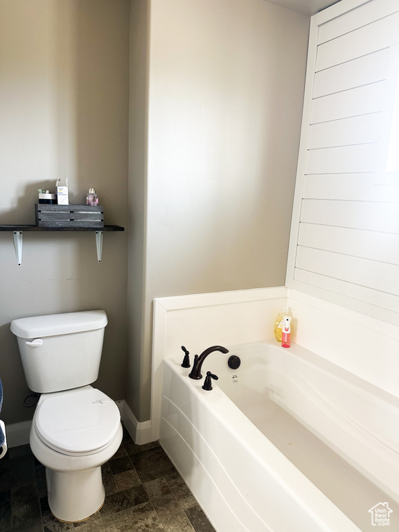 Full bath featuring a bath and stone finish floors