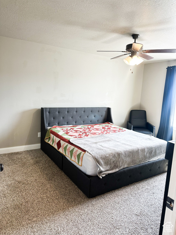 Bedroom with carpet floors, a textured ceiling, and ceiling fan