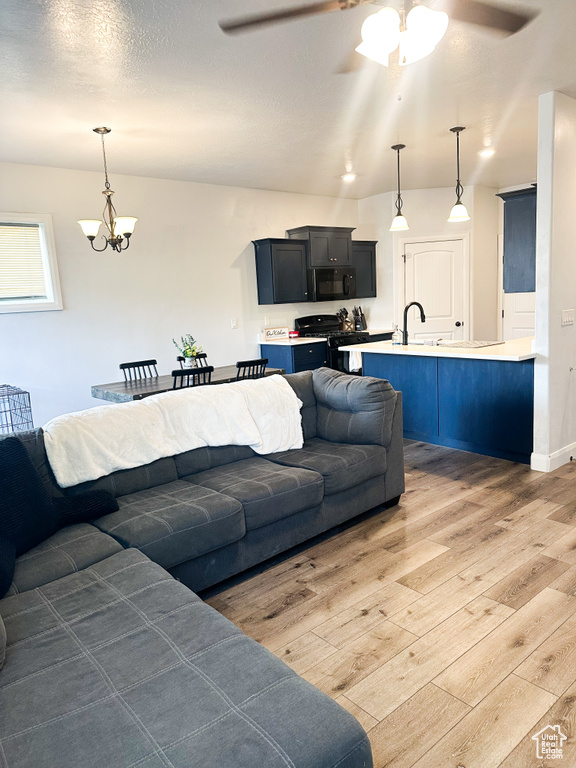 Living area featuring light wood-style floors, a ceiling fan, and a chandelier