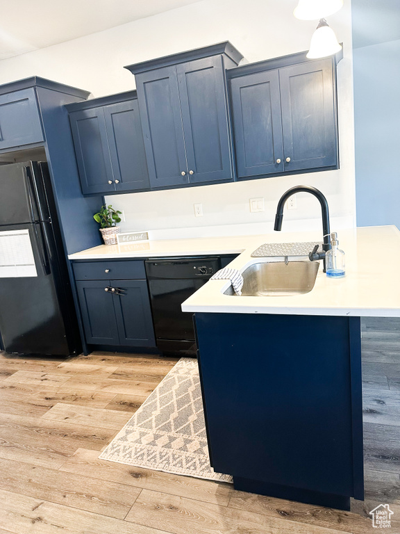 Kitchen featuring black appliances, blue cabinets, light countertops, and a peninsula