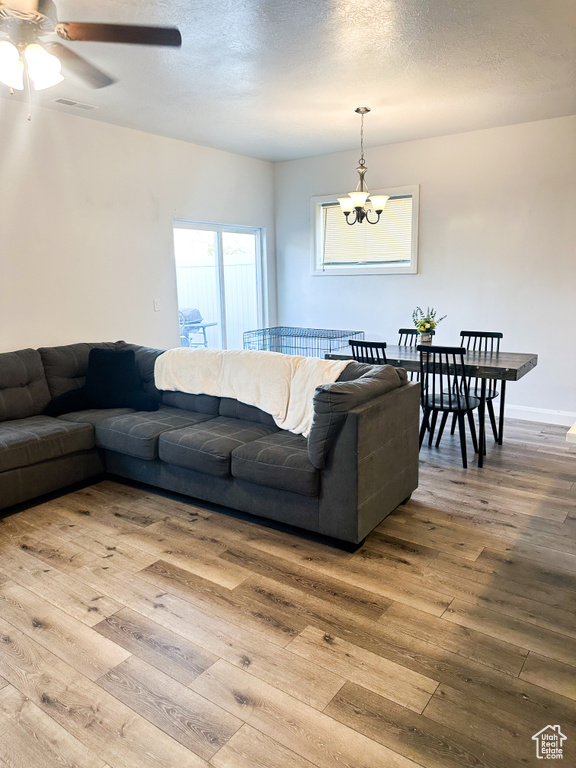 Living room with wood-type flooring, a ceiling fan, and a chandelier