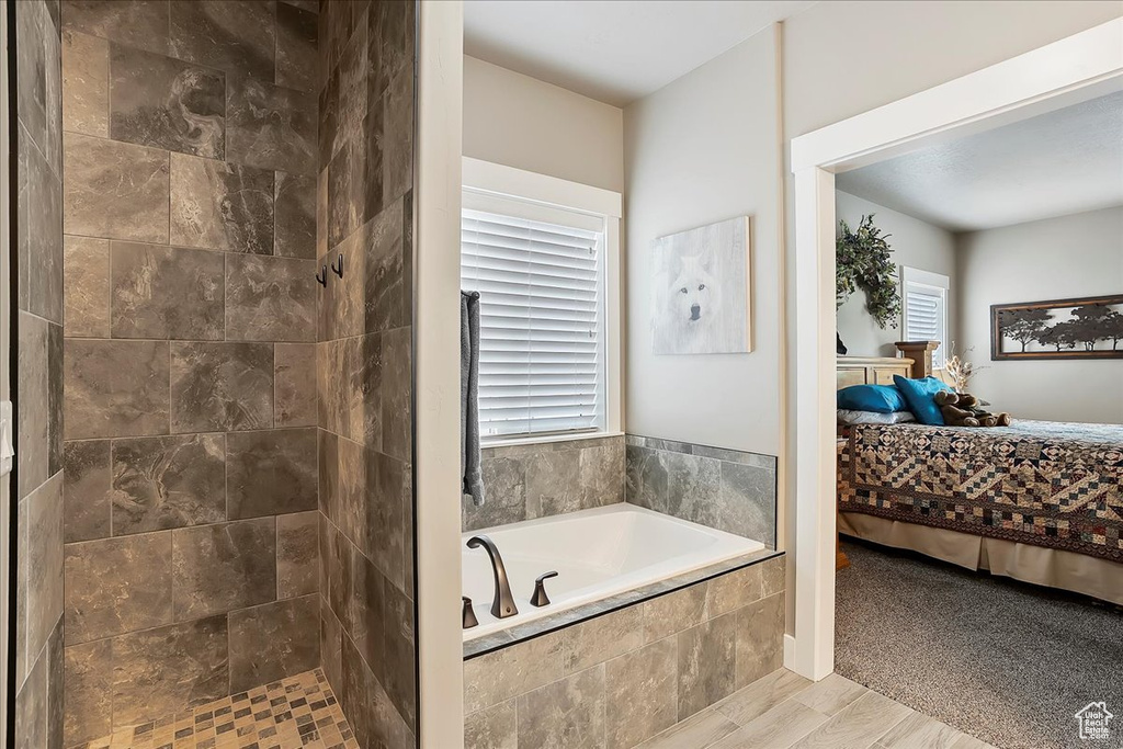 Bathroom with connected bathroom, a bath, tiled shower, and healthy amount of natural light