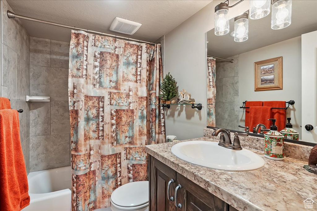 Bathroom with toilet, vanity, and shower / tub combo with curtain
