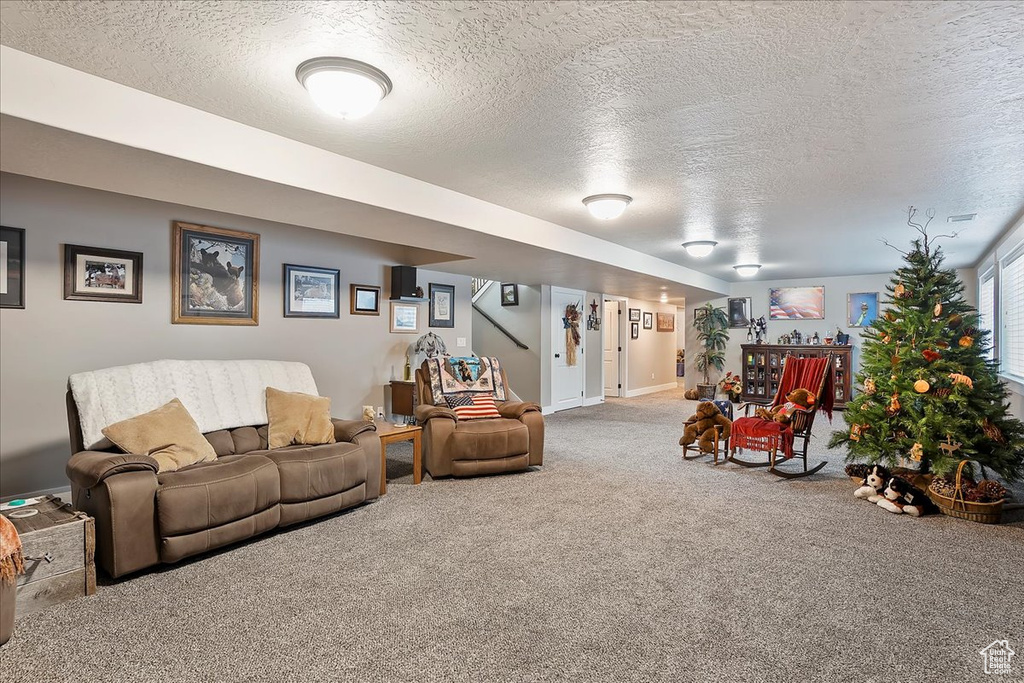 Living area with a textured ceiling, carpet floors, stairs, and baseboards