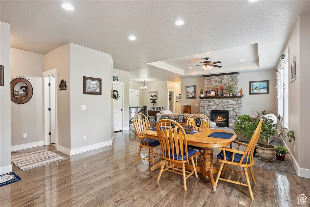 Dining room featuring baseboards, wood finished floors, a fireplace, ceiling fan, and recessed lighting