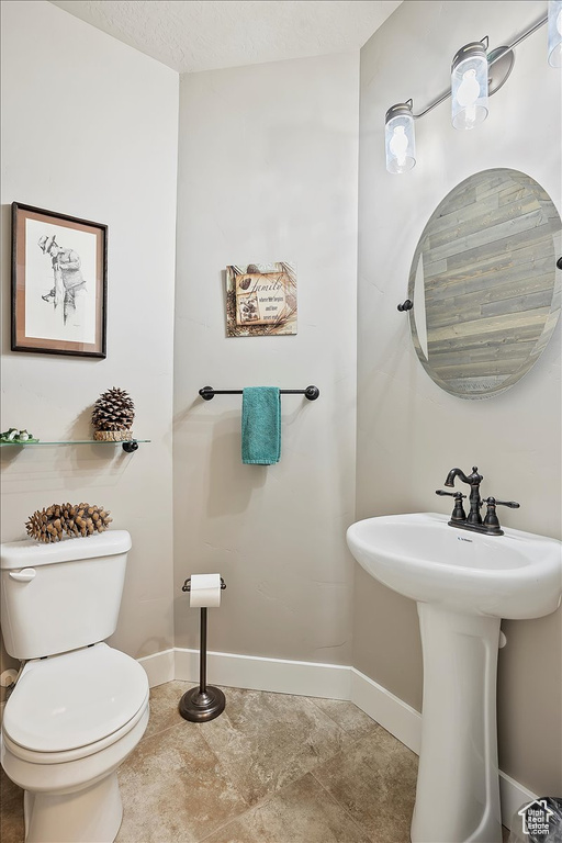 Half bath with toilet, baseboards, and a sink