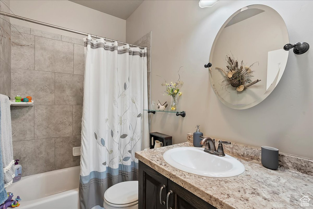 Bathroom featuring toilet, shower / bath combination with curtain, and vanity