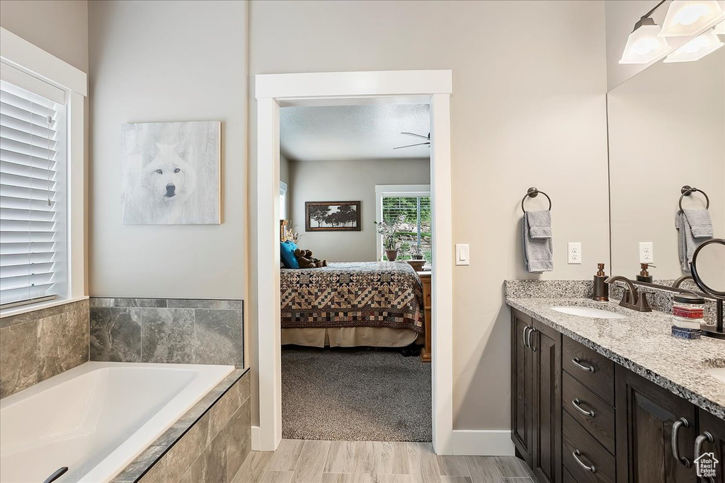 Full bathroom with ensuite bathroom, a garden tub, ceiling fan, and double vanity