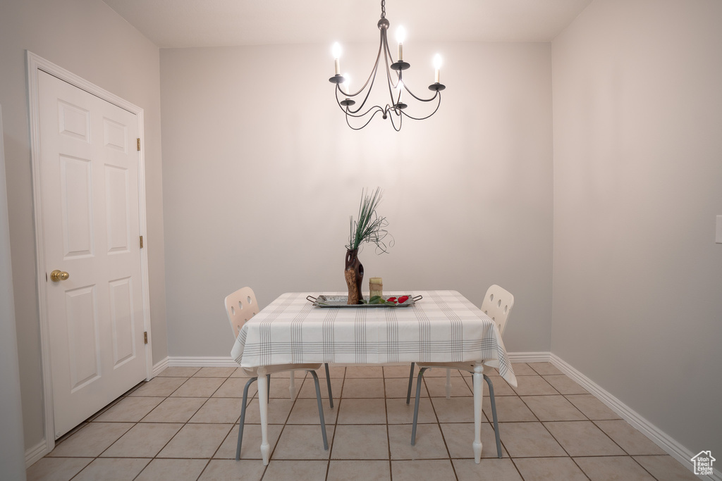 Dining space with a chandelier, light tile patterned floors, and baseboards