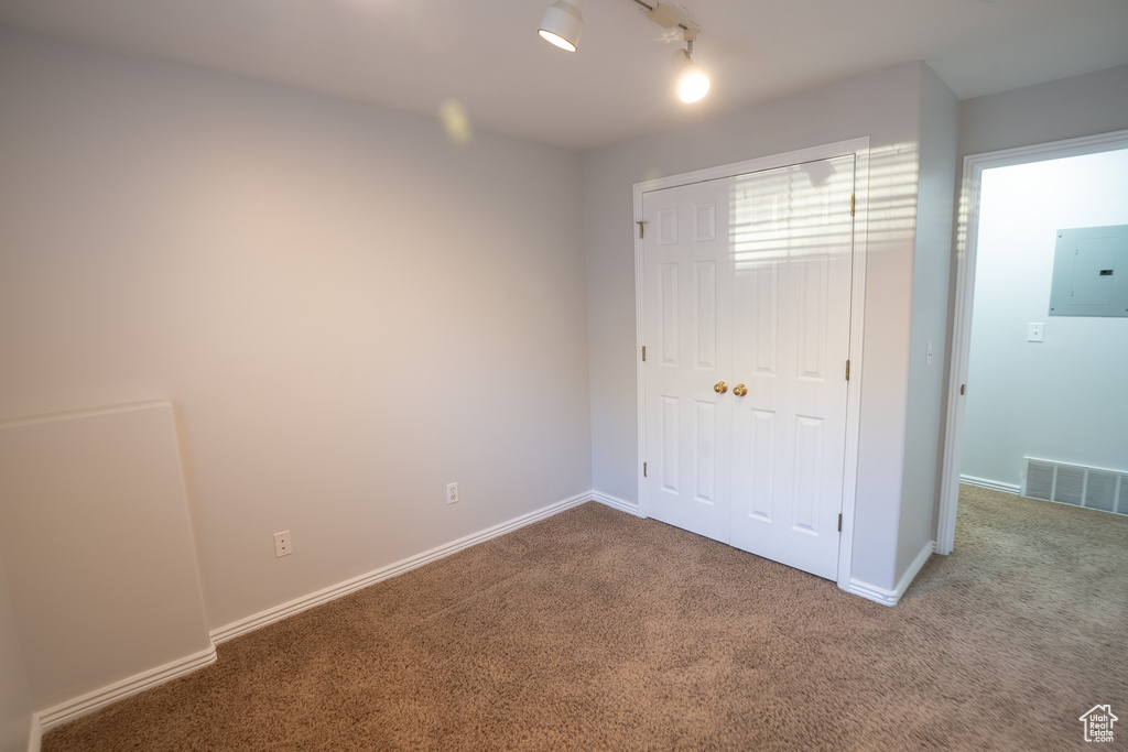 Unfurnished bedroom with electric panel, carpet flooring, a closet, and baseboards