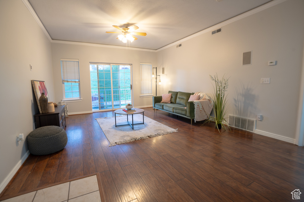 Living room featuring ceiling fan, hardwood / wood-style flooring, baseboards, and ornamental molding