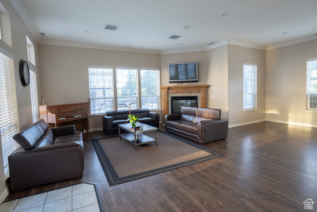 Living area with wood finished floors, crown molding, a glass covered fireplace, and baseboards