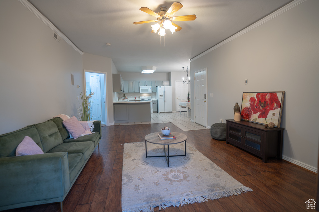 Living room with crown molding, light wood-type flooring, ceiling fan, and baseboards