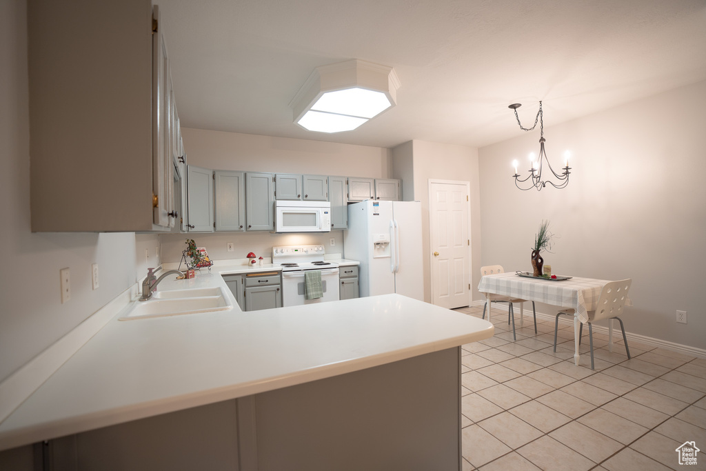 Kitchen with white appliances, a sink, light tile patterned floors, light countertops, and a peninsula