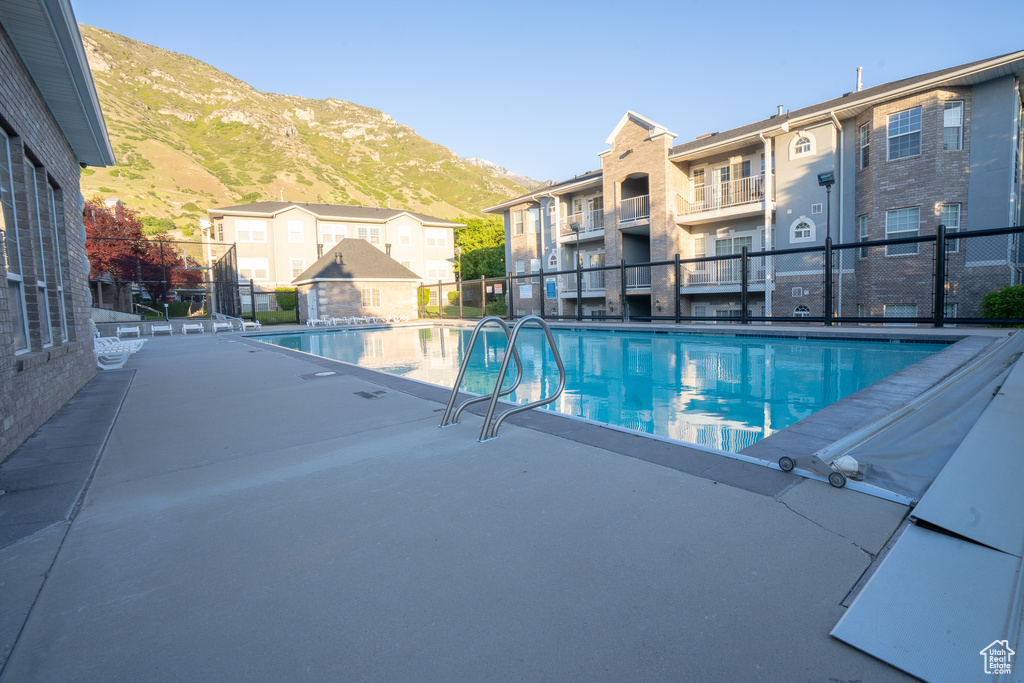 Community pool with a mountain view, a patio area, and a residential view