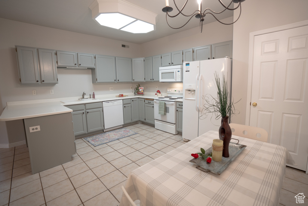 Kitchen with white appliances, light tile patterned floors, light countertops, gray cabinetry, and a chandelier