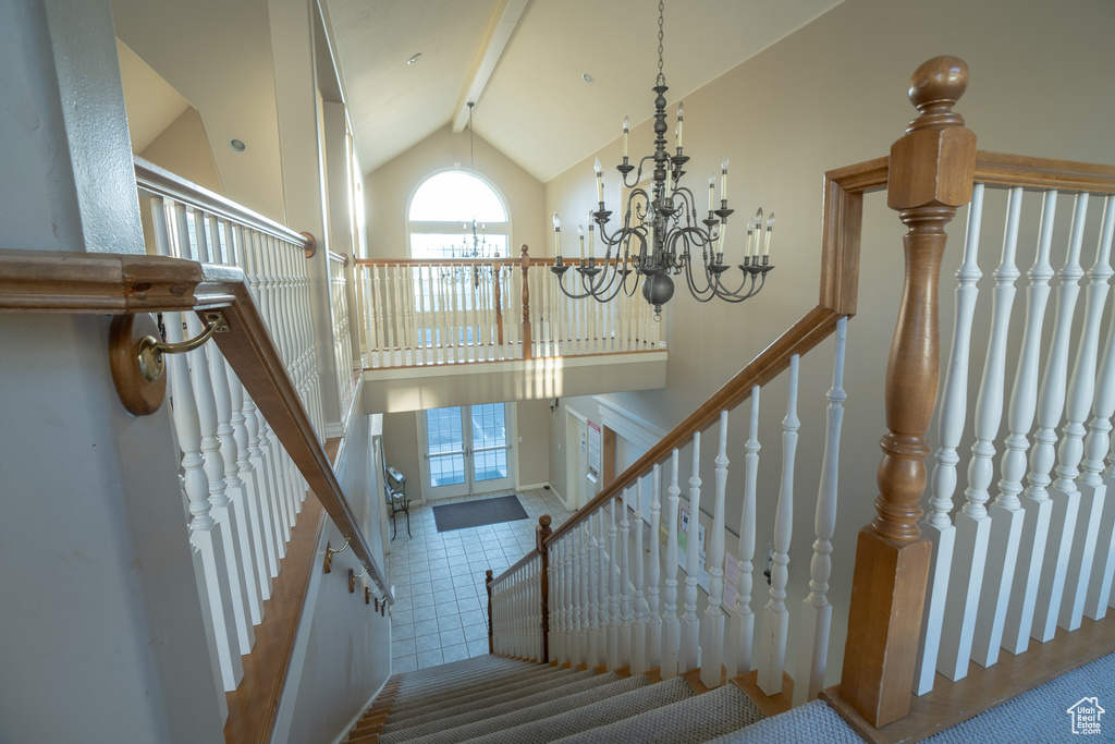 Stairway featuring a chandelier, high vaulted ceiling, and beam ceiling