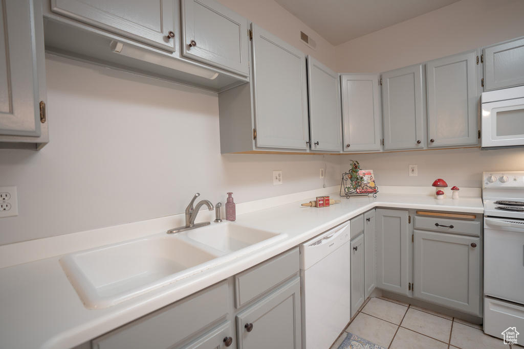 Kitchen featuring white appliances, a sink, light tile patterned floors, light countertops, and gray cabinets