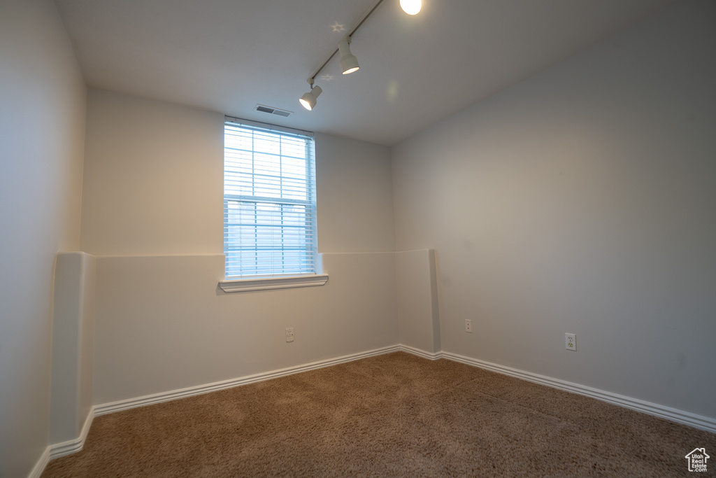 Unfurnished room featuring carpet, track lighting, and baseboards
