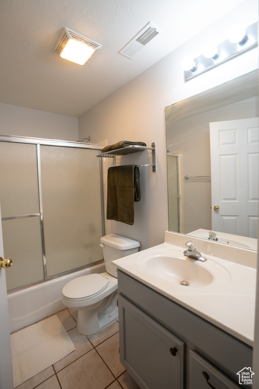 Full bath with tile patterned flooring, vanity, toilet, and enclosed tub / shower combo