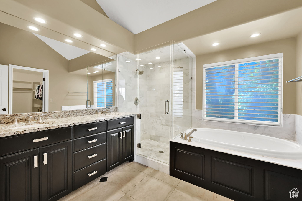 Full bathroom with tile patterned flooring, a shower stall, a garden tub, lofted ceiling, and double vanity