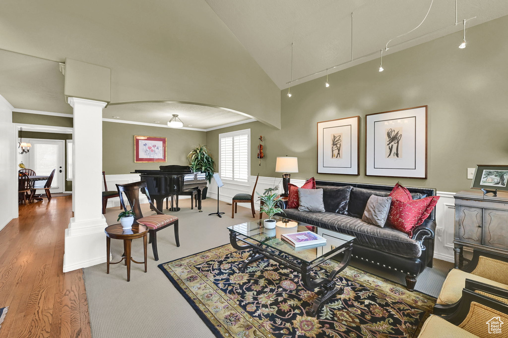 Living room featuring ornate columns, attic access, crown molding, lofted ceiling, and arched walkways