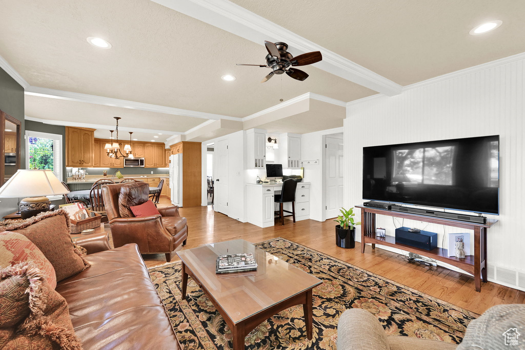 Living room featuring a chandelier, crown molding, light wood-type flooring, a ceiling fan, and recessed lighting