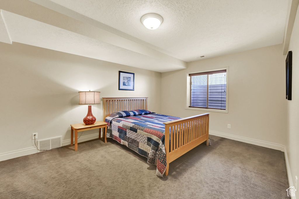 Carpeted bedroom with baseboards and a textured ceiling