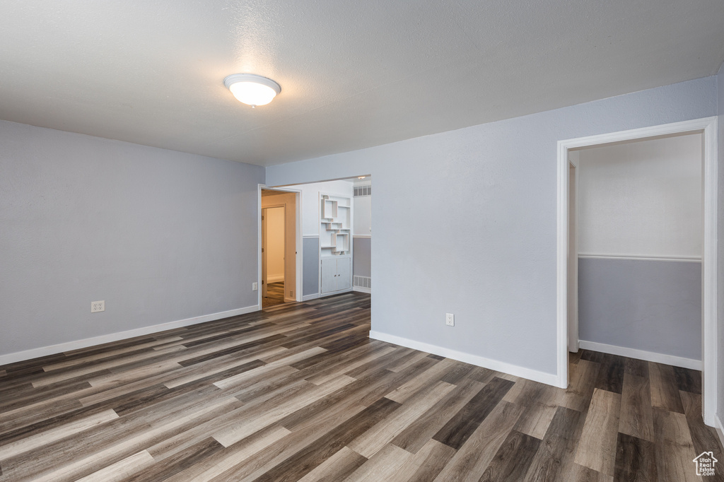 Unfurnished bedroom with dark wood-type flooring and baseboards