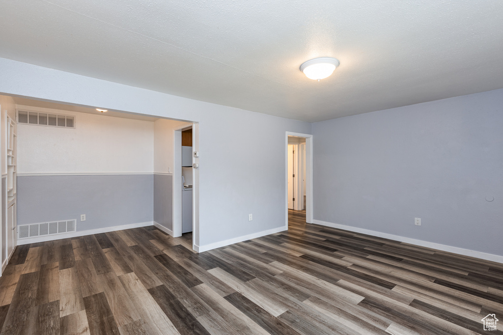 Spare room featuring dark wood-style flooring and baseboards